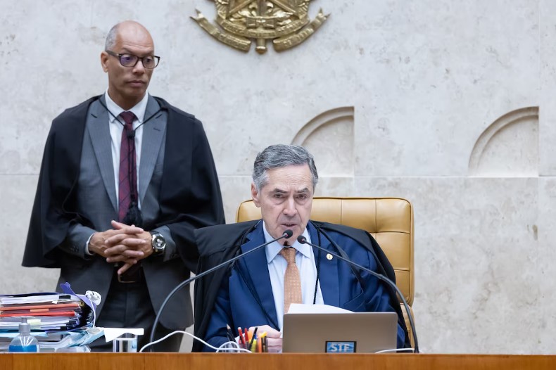 O presidente do STF, Luís Roberto Barroso (ao centro) acompanhado do assistente de plenário (ao fundo) Foto: Antonio Augusto/SCO/STF