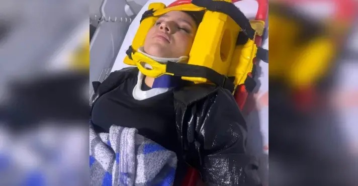 Mariana Eustáquio, filha do jornalista Oswaldo Eustáquio, veste colar cervical e imobilizador de cabeça enquanto é transportada em uma maca depois de ser ferida em um bar | Foto: Reprodução/Instagram