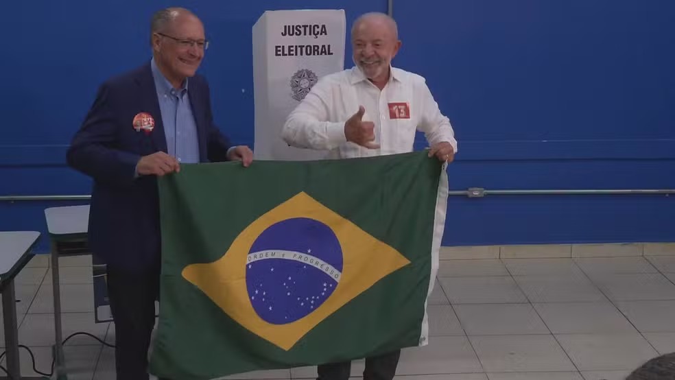 Lula vota ao lado de Alckmin segurando q bandeira do Brasil no 2º turno